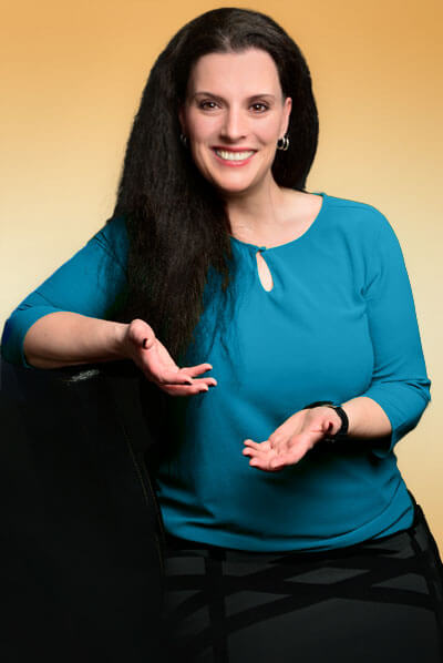 Cornelia Leclerc sitzt seitlich mit einladender Geste lächelnd, es geht um sie als Emotionscoach und Resilienzcoach